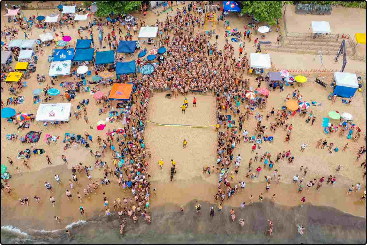 Large crowd of people gathered on a sunny beach for an event